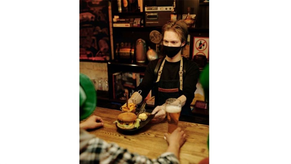 Camarero con mascarilla sirviendo la comida en un restaurante / Darlene Alderson en Pexels