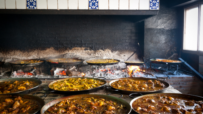 Diferentes paellas valencianas cocinándose a la leña / Foto: Canva