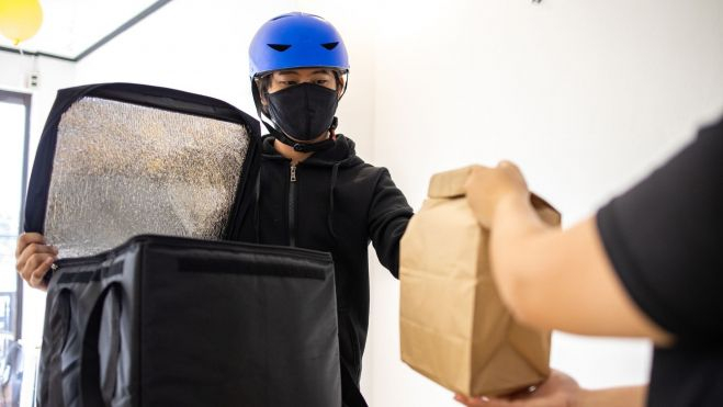 Un repartidor entregando un paquete de comida / Foto: Canva