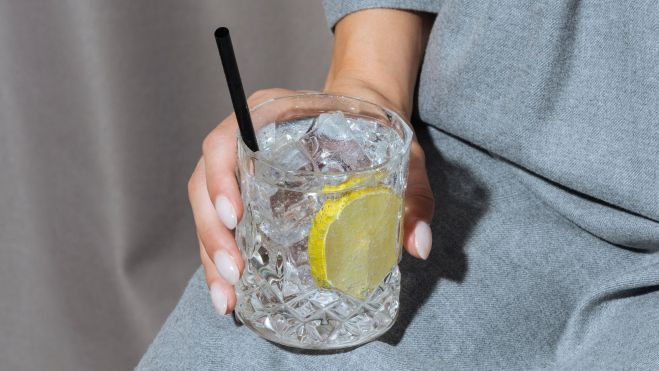 Gin tonic en el regazo de una mujer / Foto: Canva