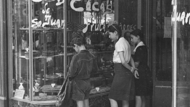 Foto antigua de niños mirando las cocas de San Juan del escaparate de una pastelería de Barcelona / Foto: Pinterest