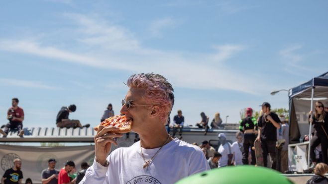 Un hombre come pizza bajo el sol / Foto: Pexels