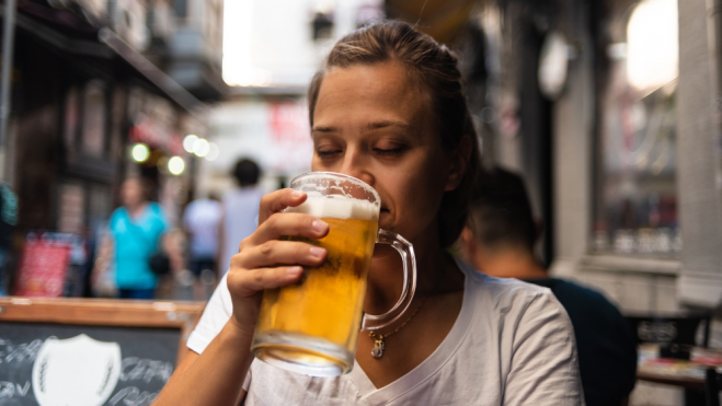 Chica tomando una jarra de cerveza / Foto: Canva