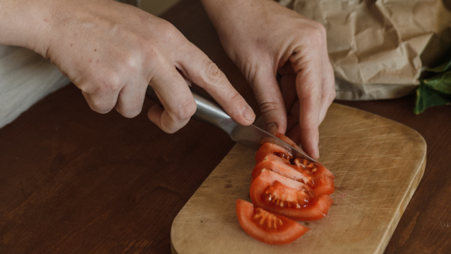 Persona cortando tomates / Foto: Pexels