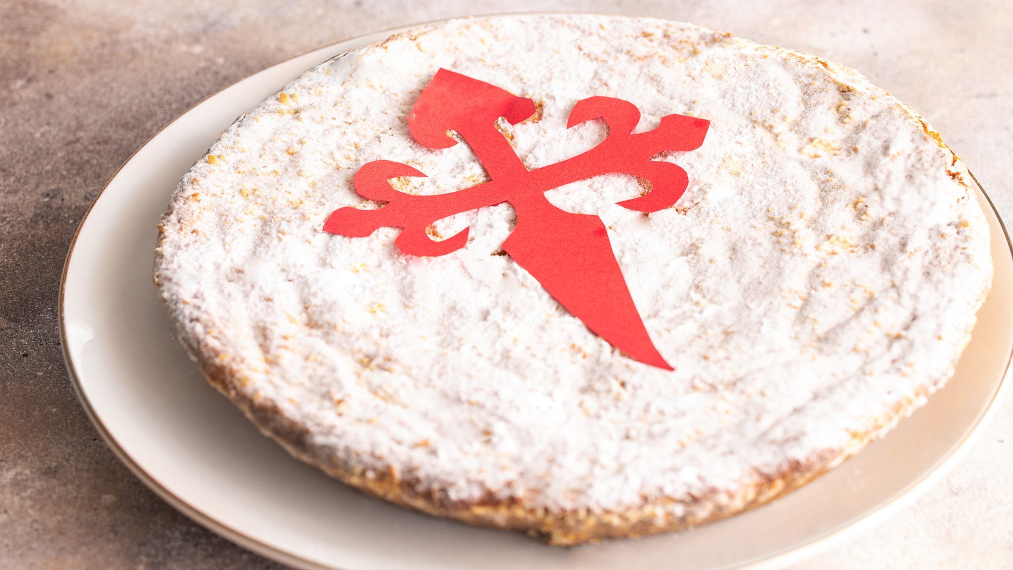 Tarta de Santiago aún con el molde de la cruz / Foto: Canva  / Receta paso a paso del típico postre gallego