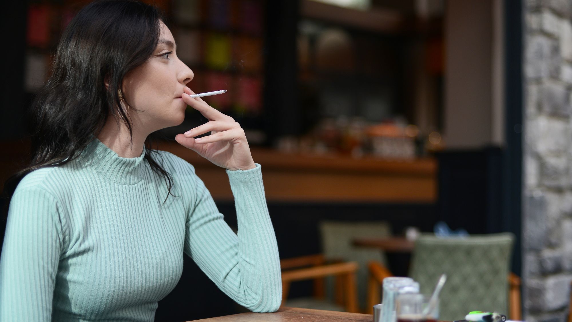 Mujer fumando en la terraza de un bar / Foto: Canva / Cataluña prohibirá fumar en las terrazas