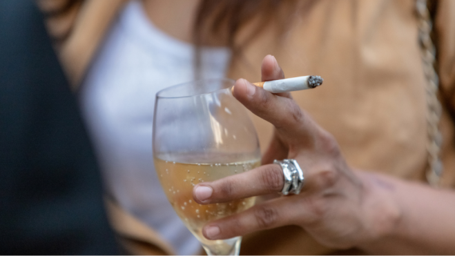 Mujer sujetando una copa y un cigarro en una terraza/ Foto: Canva