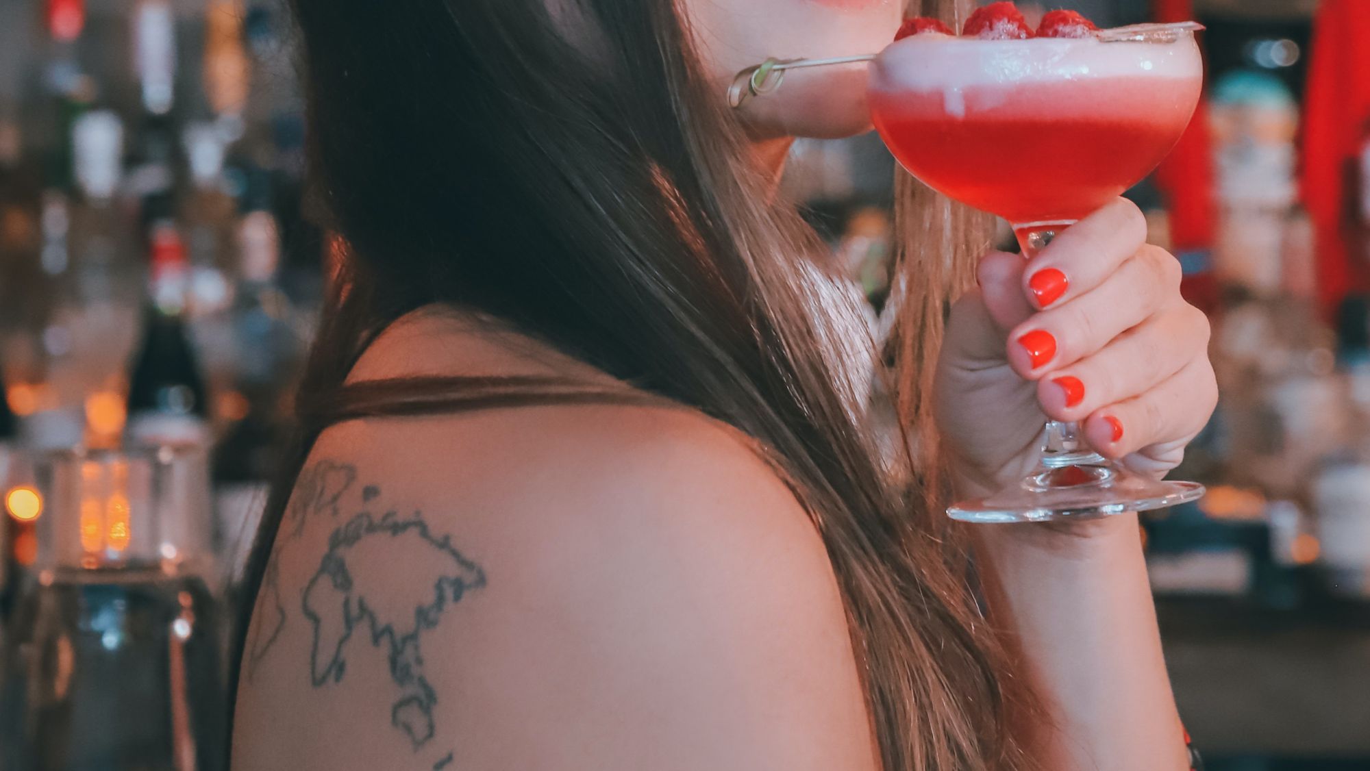 Mapamundi tatuado y cóctel en la mano / Foto: Pexels / Bares locales en listas globales