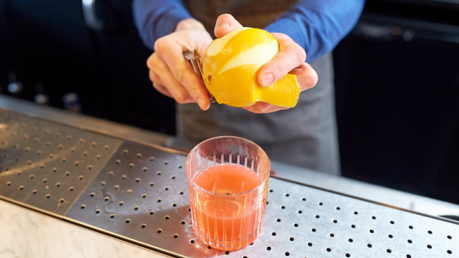 Bartender pelando un limón para un cóctel / Foto: Canva