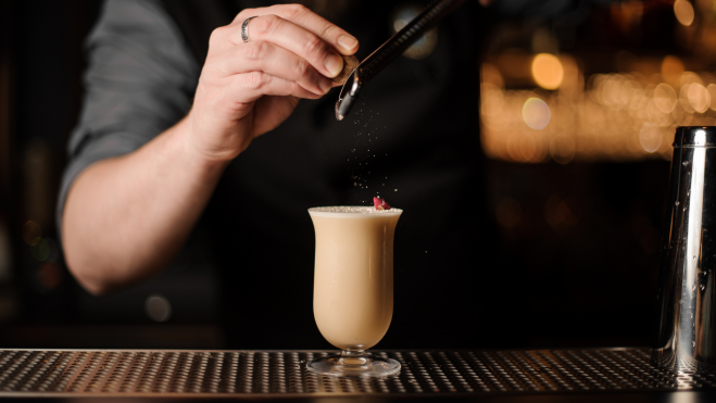 Bartender rallando nuez moscada en un cóctel / Foto: Canva