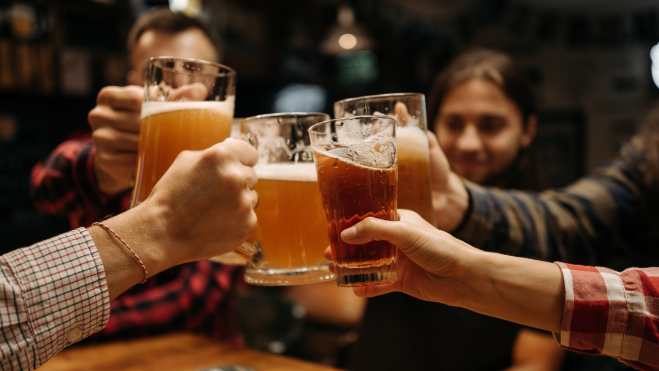 Personas brindando con jarras de cerveza en un pub / Foto: Pexels