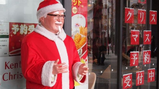 Carteles que anuncian los menús de Navidad de KFC y una figura del Coronel Sanders vestido de Papa Noel