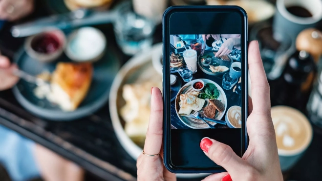 Comensal fotografiando su comida en un restaurante / Foto: Canva