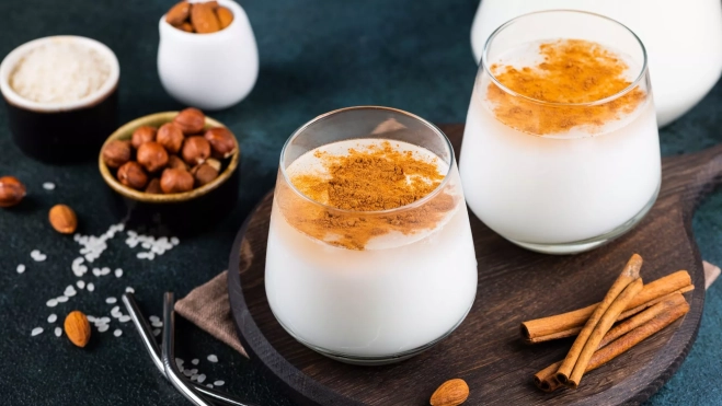 Vasos de horchata con chufa y canela espolvoreada y en rama / Foto: Canva