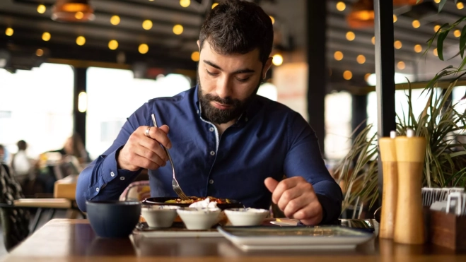 Hombre comiendo solo en un restaurante / Foto: Canva