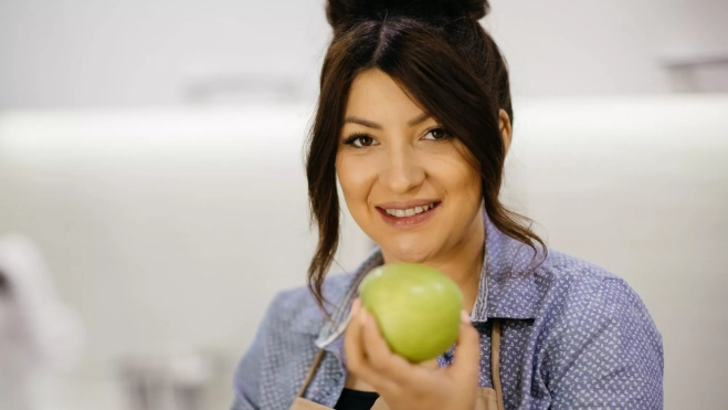 Mujer a punto de comerse una manzana / Foto: Canva