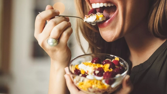 Mujer desayunando un bol con yogur y frutas / Foto: Canva
