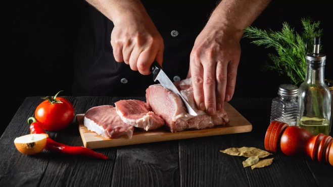 Cocinero cortando carne de cerdo / Foto: Canva