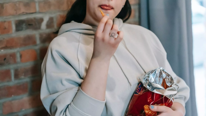 Mujer comiendo un snack de bolsa / Foto: Pexels