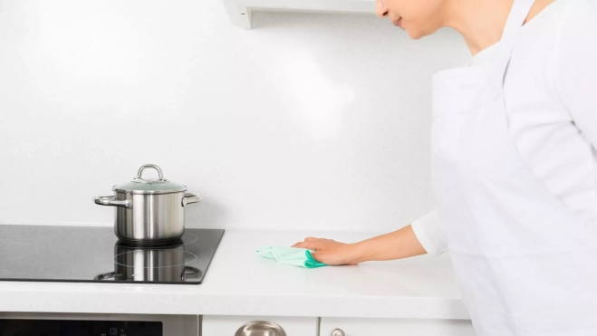 Mujer limpiando la encimera de una cocina / Foto: Canva