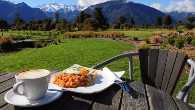 Plato caliente y café con vistas a una montaña / Foto: Canva