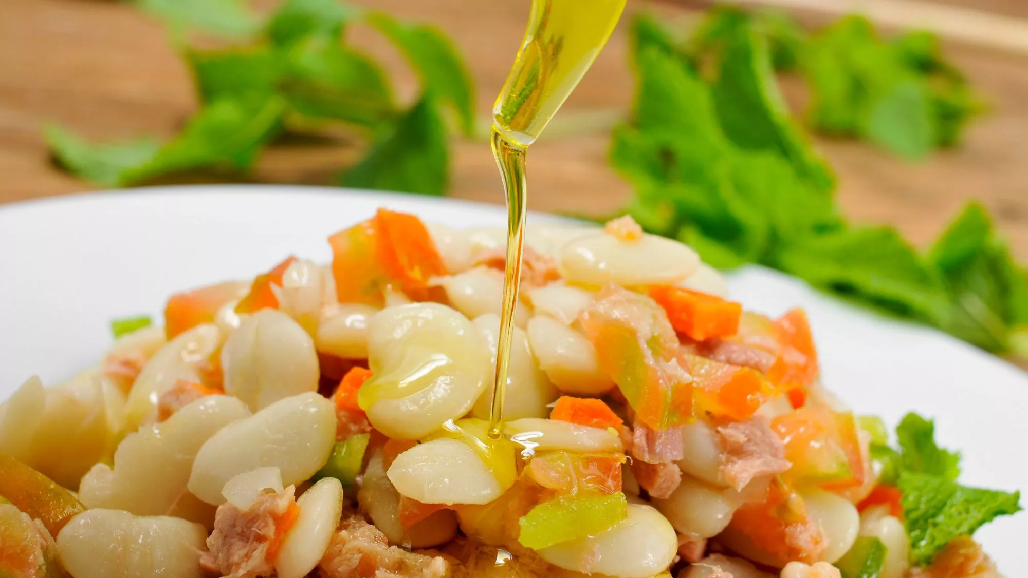 Plato de 'empedrat' aderezado con aceite de oliva / Canva / Cómo preparar el 'empedrat': la ensalada catalana con bacalao que está lista en 15 minutos