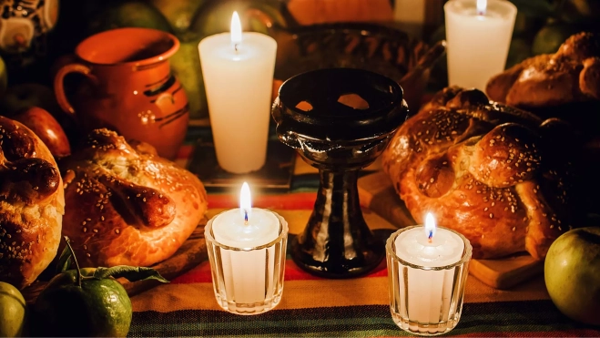 Pan de muerto, velas y fruta en un altar de muertos mexicano / Canva Pan de muerto, velas y fruta en un altar de muertos mexicano / Canva