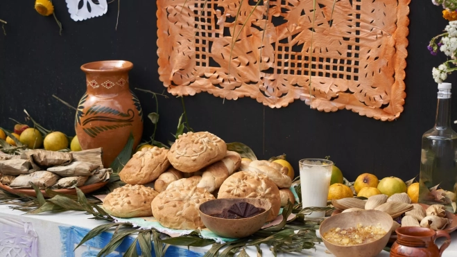 Tamales, pan de muerto y otras ofrendas en un altar de muertos mexicano / Canva Tamales, pan de muerto y otras ofrendas en un altar de muertos mexicano / Canva
