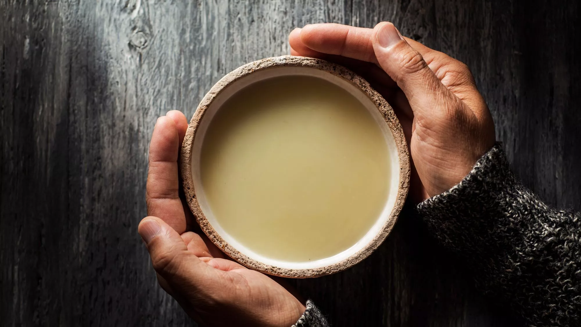 Manos sujetando un cuenco de sopa caliente / Canva