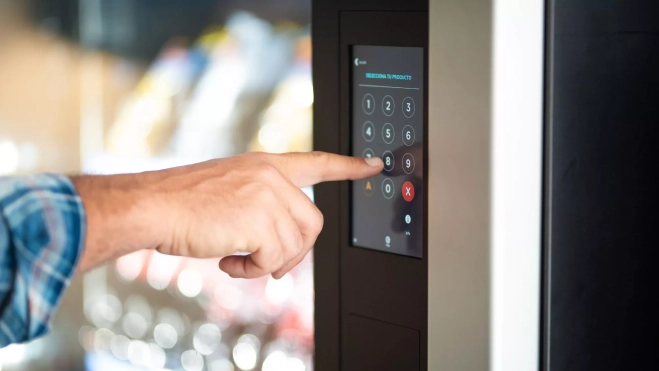 Hombre seleccionando un producto en una máquina de vending / Canva