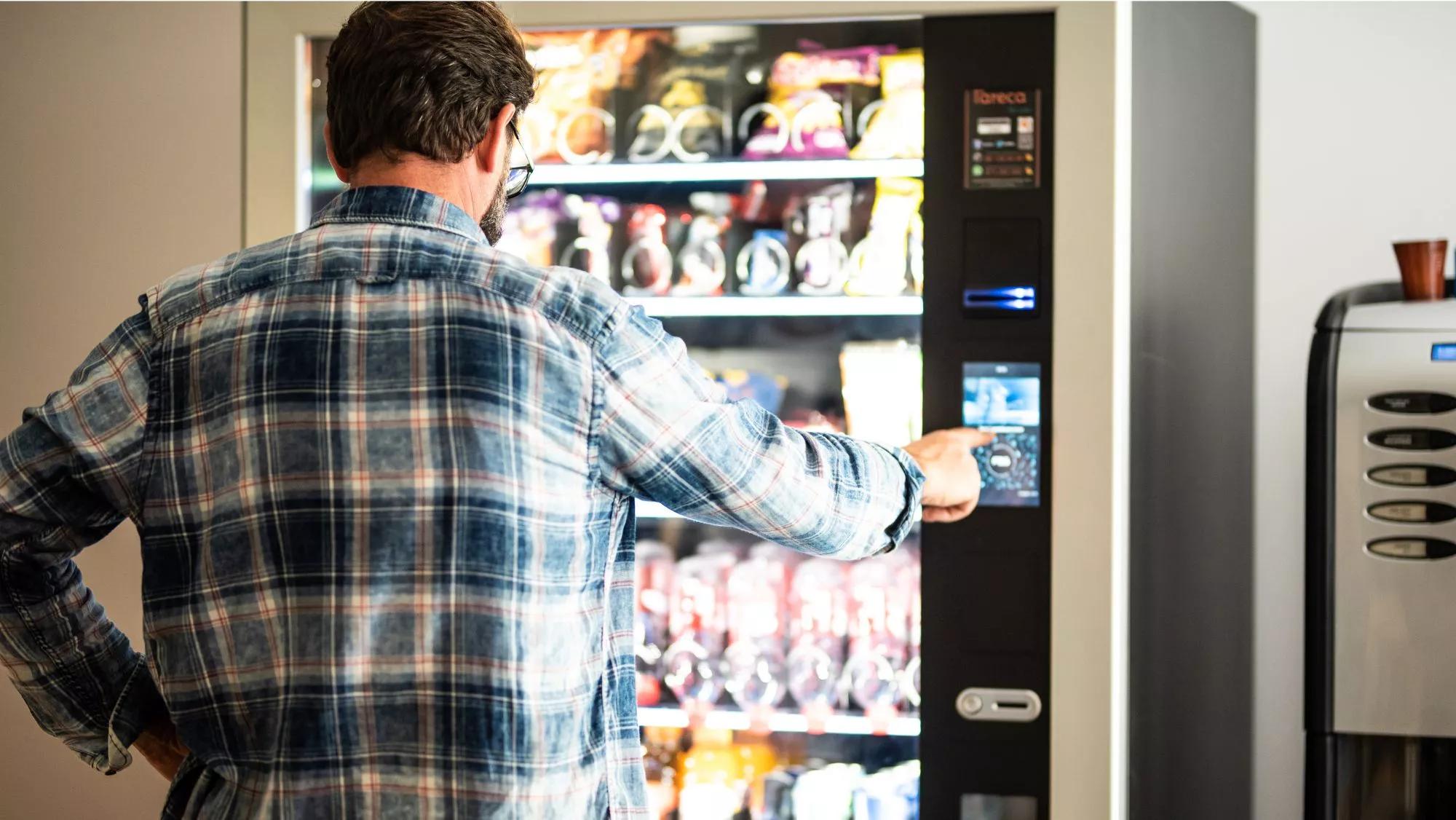 Hombre seleccionando un producto en una máquina de vending / Canva