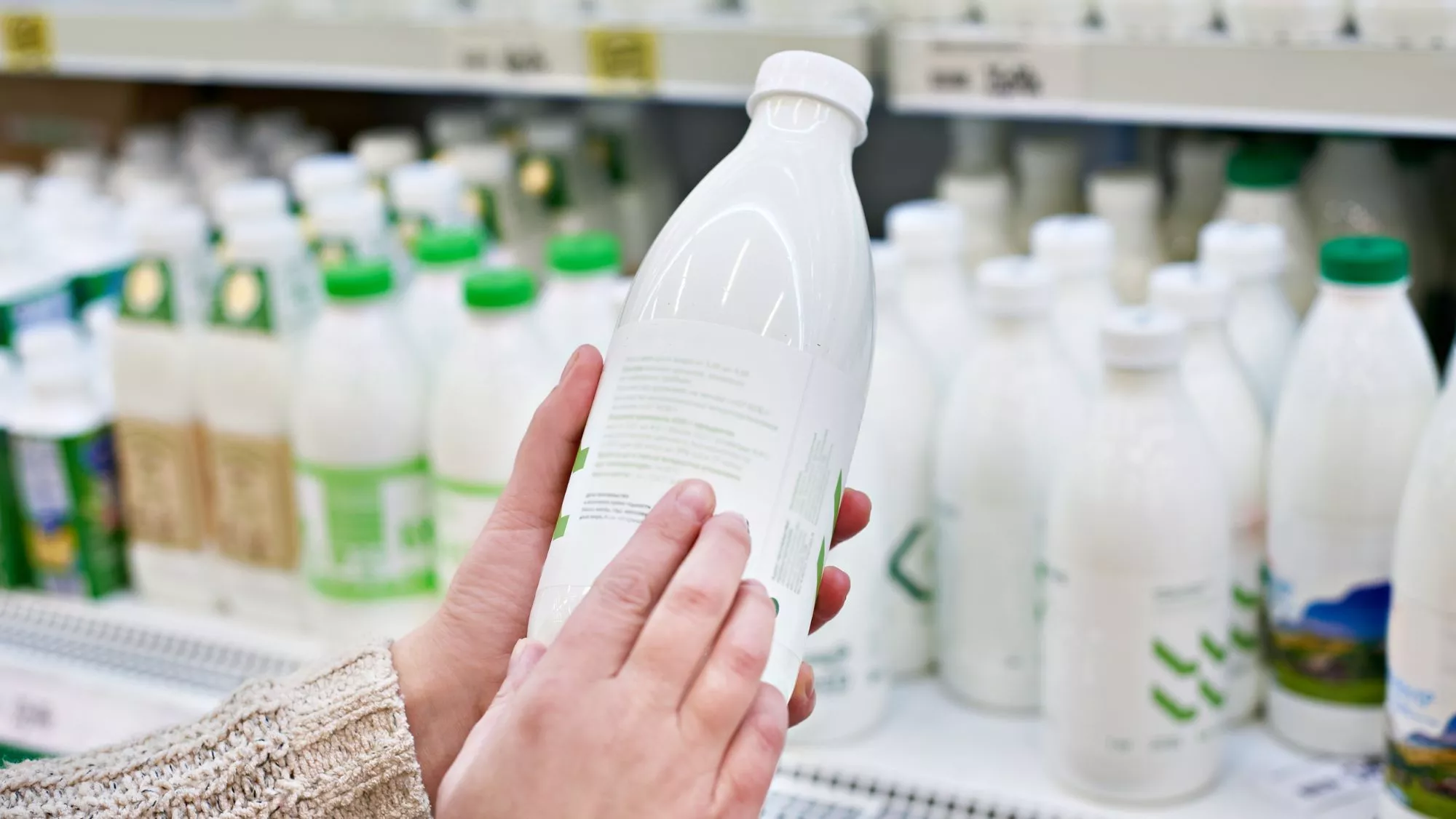 Mujer revisando la etiqueta y la fecha de caducidad de una botella de leche en un supermercado / Canva / El 69% de los españoles come alimentos caducados: cómo saber si un producto ya no es seguro