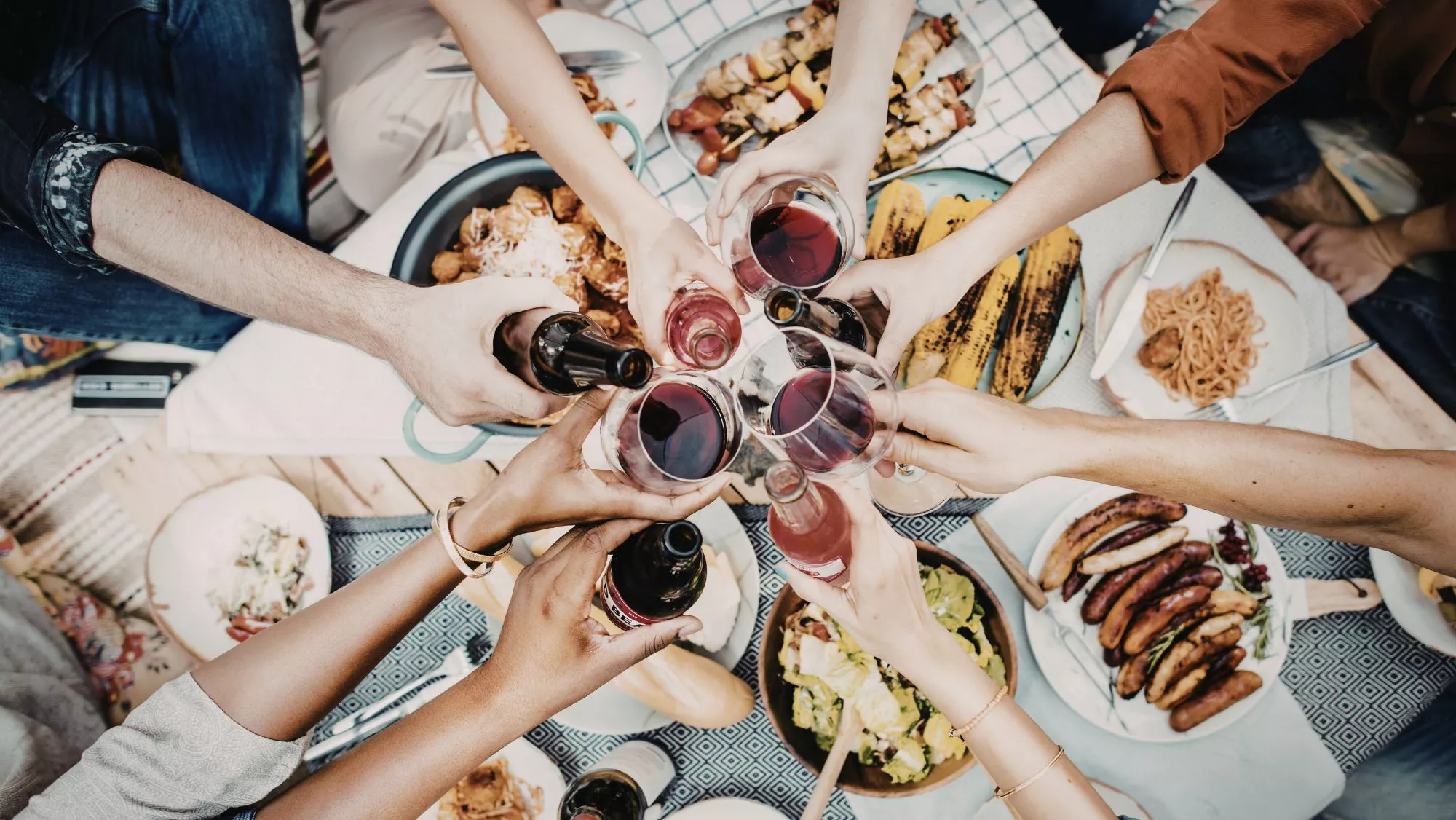 Brindis entre amigos en una celebración gastronómica / Canva
