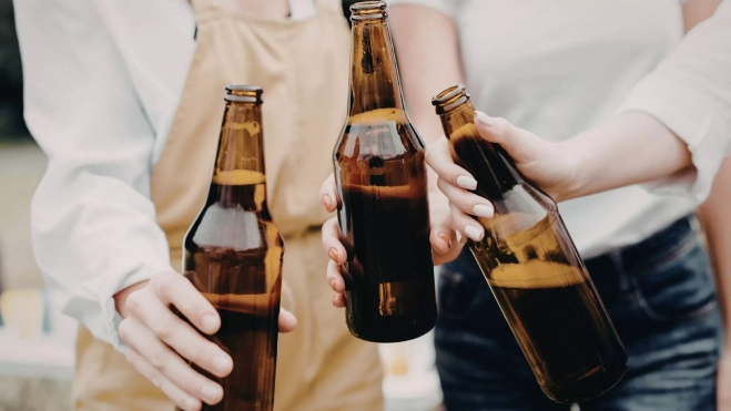 Amigos disfrutando de unas cervezas en una fiesta al aire libre / Canva
