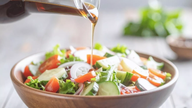Aliño de jugo de pepinillos en una ensalada verde / CANVA