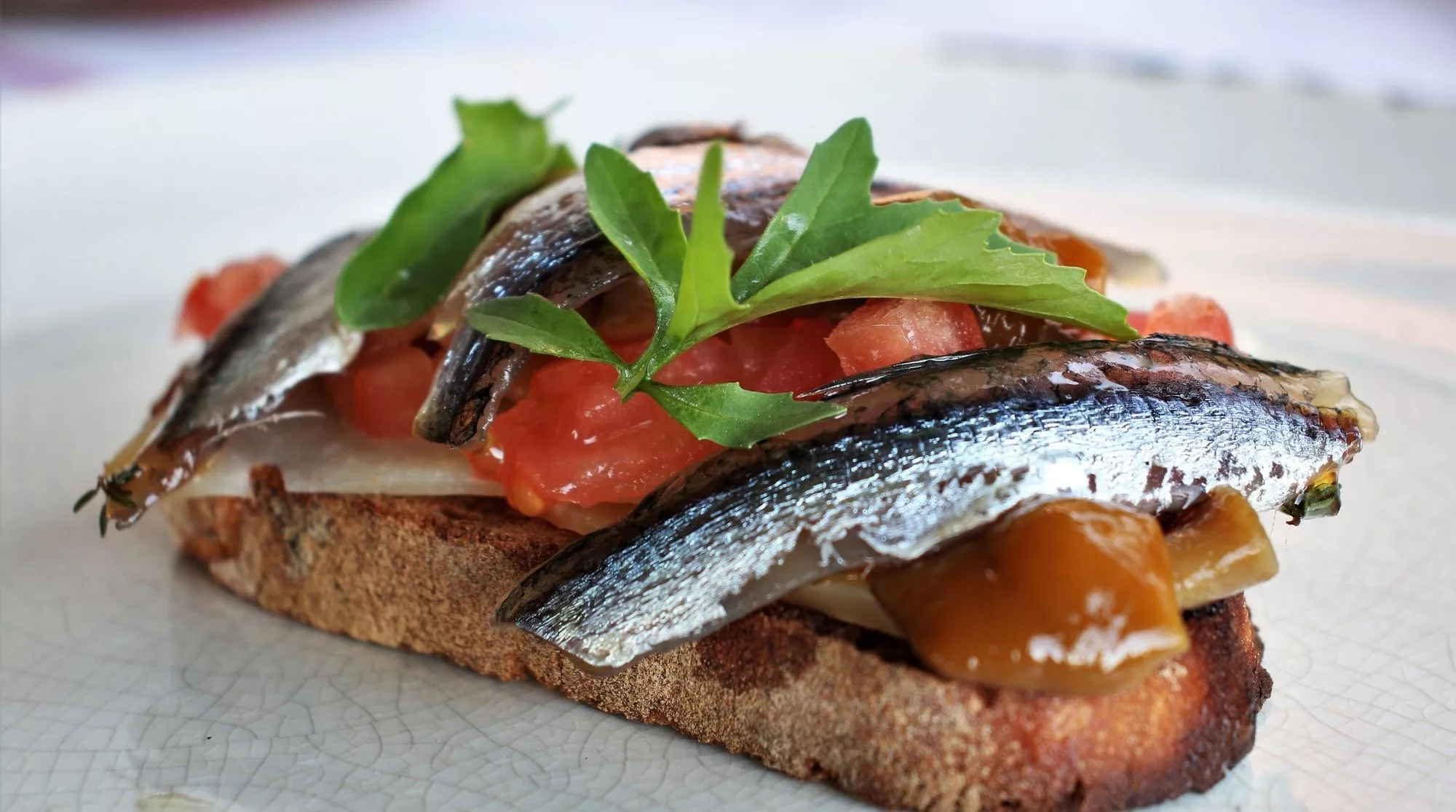 Tostada de boquerones con queso de oveja,  tomate brunoise y rossinyols. Receta de Inés Butrón / Antonio Ron