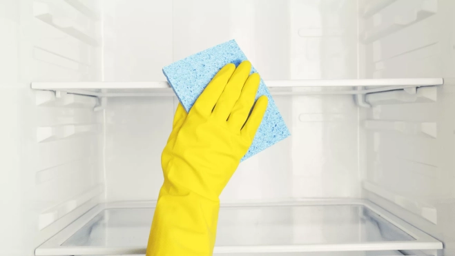 Mano con guantes amarillos con estropajo azul | Canva Mano con guantes amarillos con estropajo azul | Canva